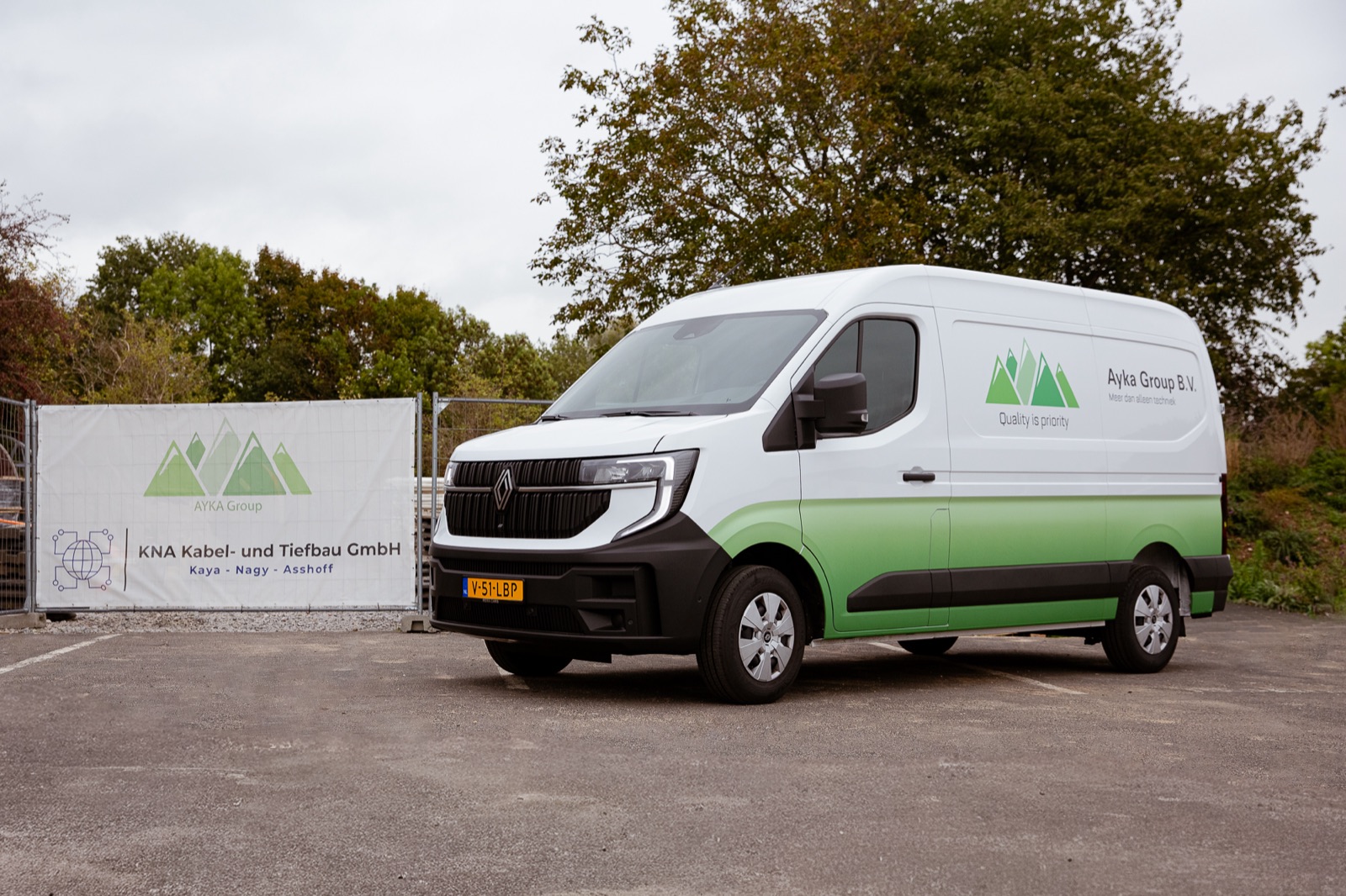 Ayka Group bedrijfsbus op een projectlocatie naast een partner bord